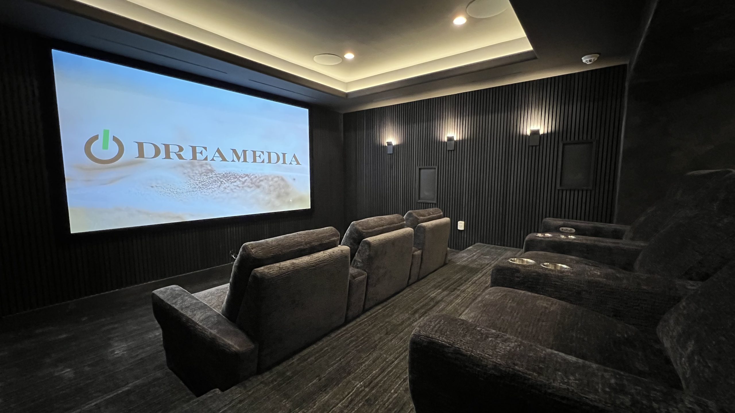 Luxury home theater featuring plush seating and a large projection screen with the Dreamedia logo prominently displayed.