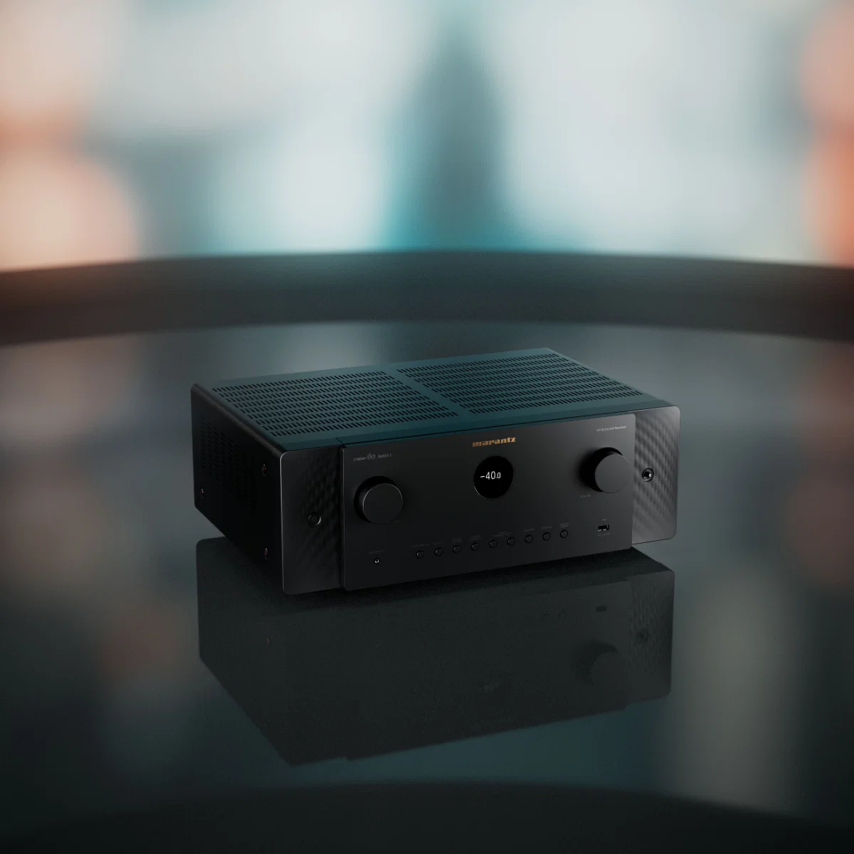 A sleek Marantz home theater amplifier with illuminated display and controls, reflecting on a dark surface.