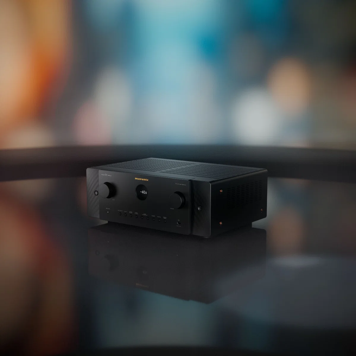 Black Marantz home theater amplifier on a reflective surface, showcasing sleek design and premium audio quality.