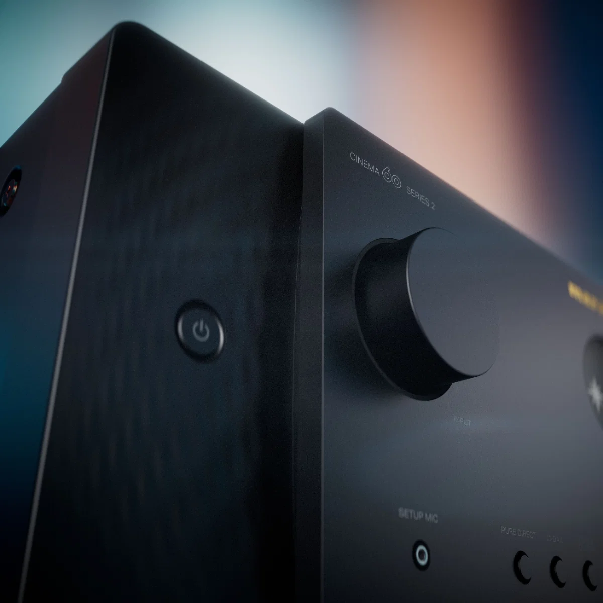 Close-up of a premium home theater amplifier with control knob and power button, showcasing sleek design and advanced features.