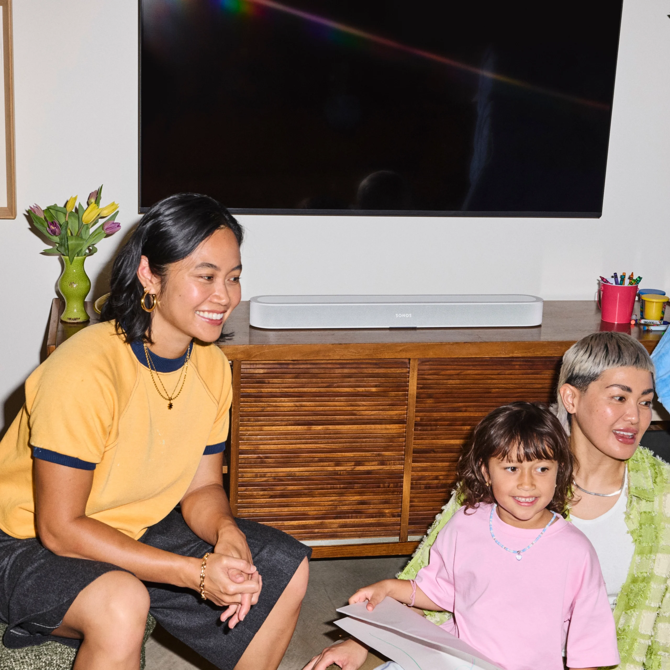 A family enjoys quality time together in a cozy living room with a stylish soundbar and vibrant decor.