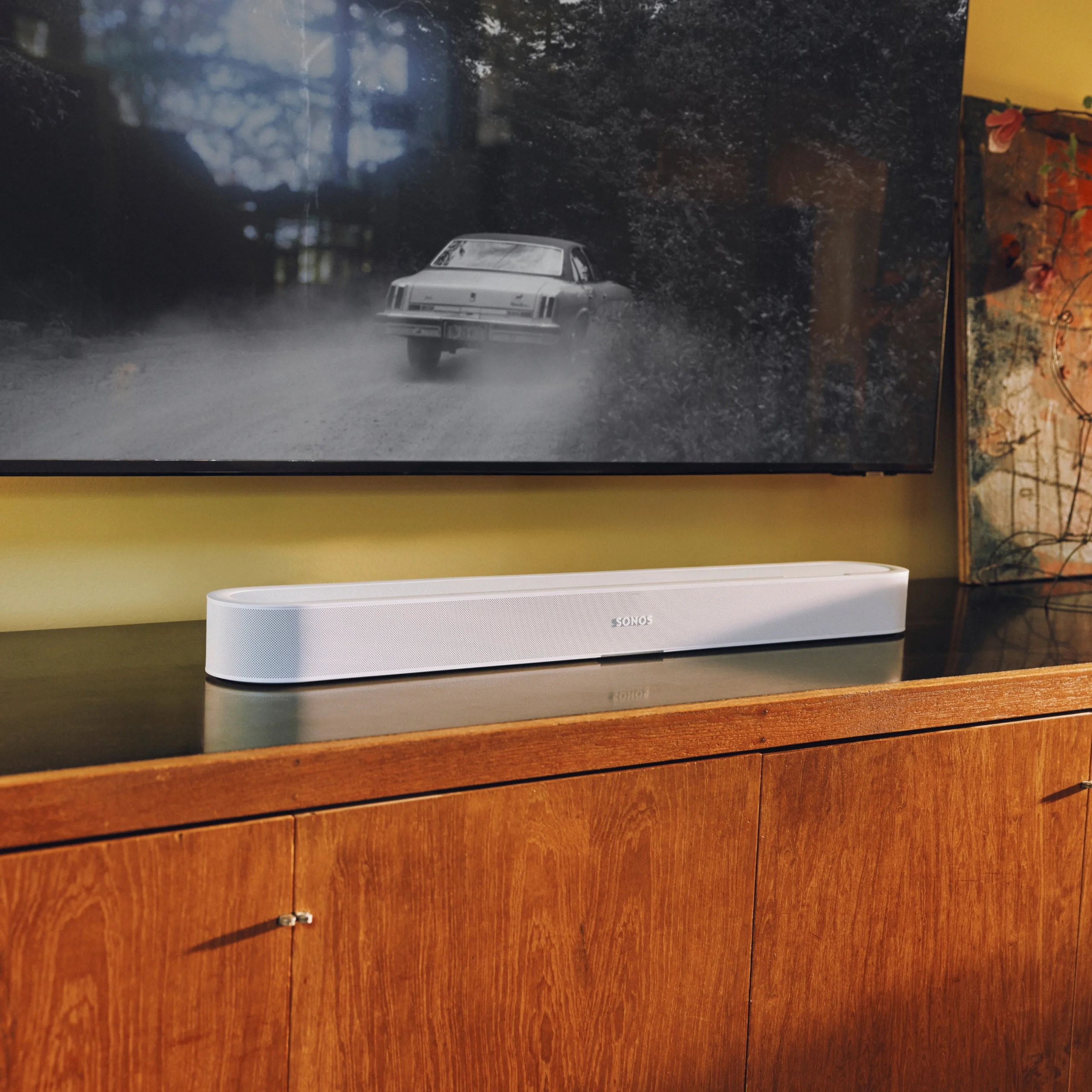 A sleek Sonos soundbar on a wooden cabinet, complementing a modern home theater setup with vintage decor.