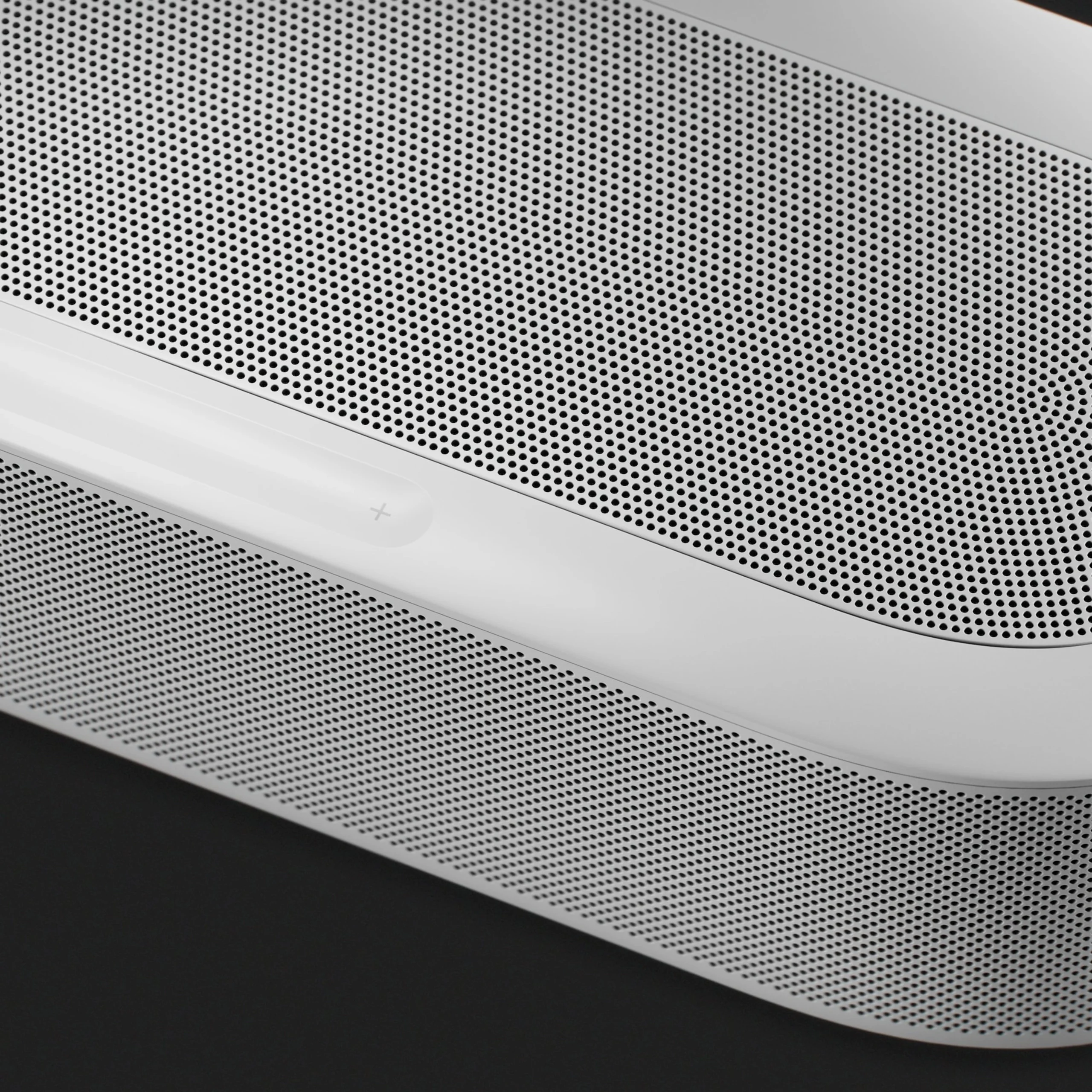 Close-up of a sleek, white speaker with a perforated metallic grille, showcasing modern audio design and premium build quality.