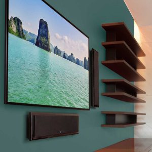 Modern home theater setup featuring a large wall-mounted TV and sleek speakers on a teal accent wall.